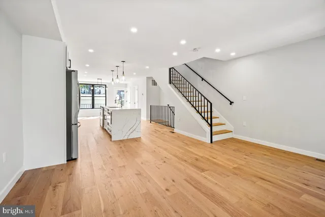 a view of a living room with wooden floor and stairs