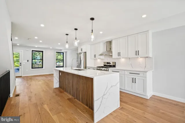 a open kitchen with kitchen island a sink a center island and wooden floor