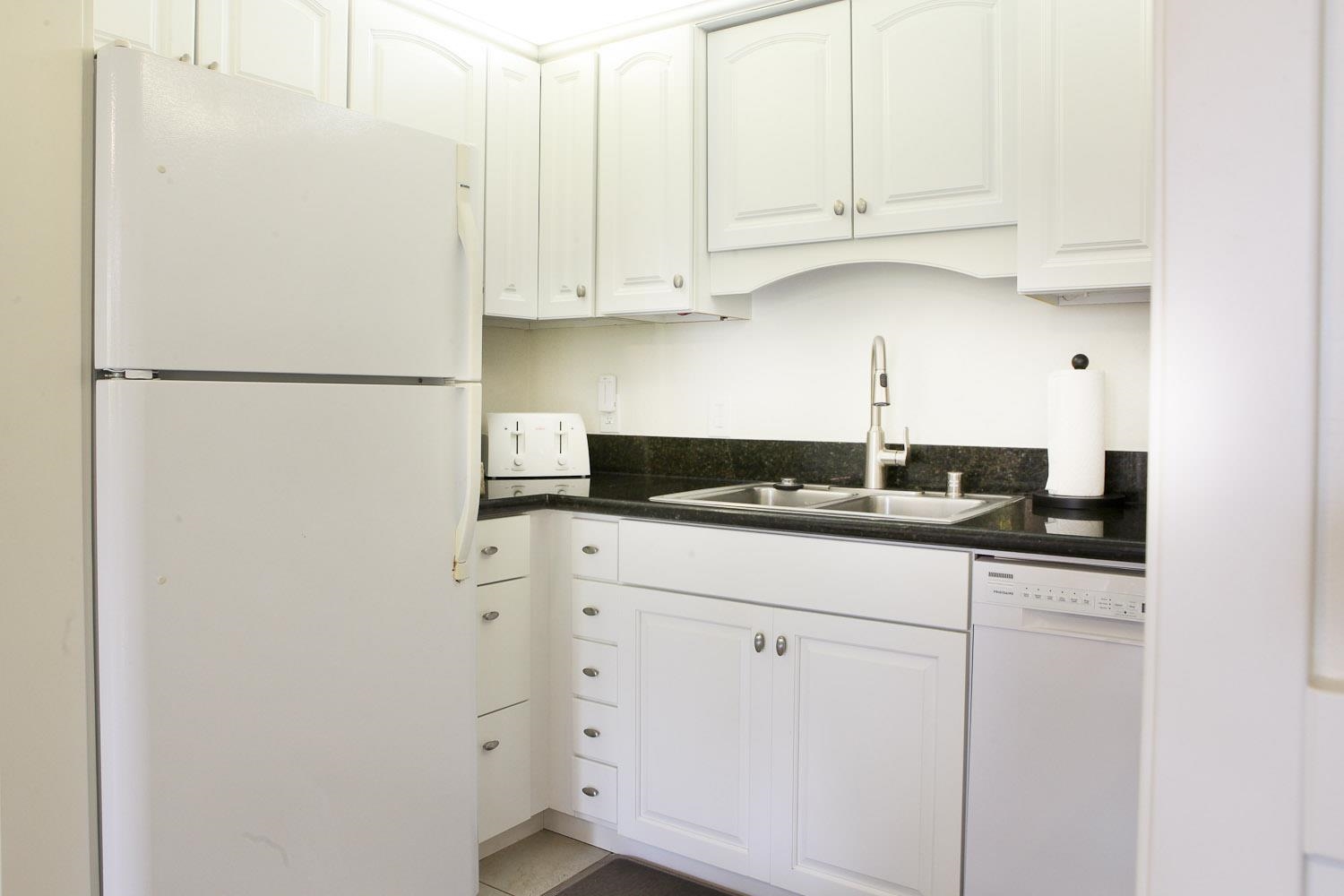 115 North Kihei Road, Unit A3 Kihei, HI 96753 - Photo 9 of 21 a kitchen with granite countertop white cabinets and refrigerator