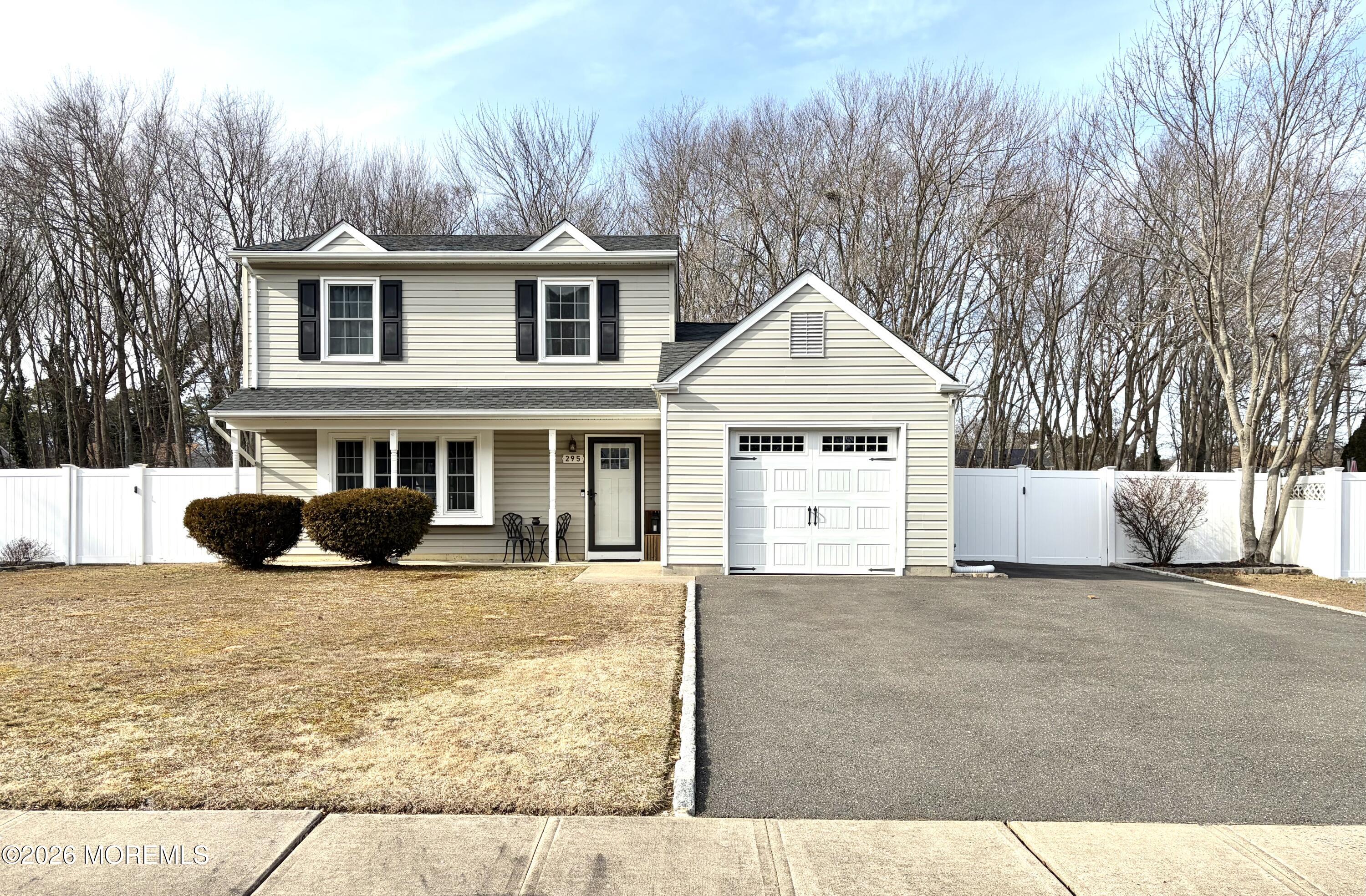 a front view of a house with yard and trees in the background