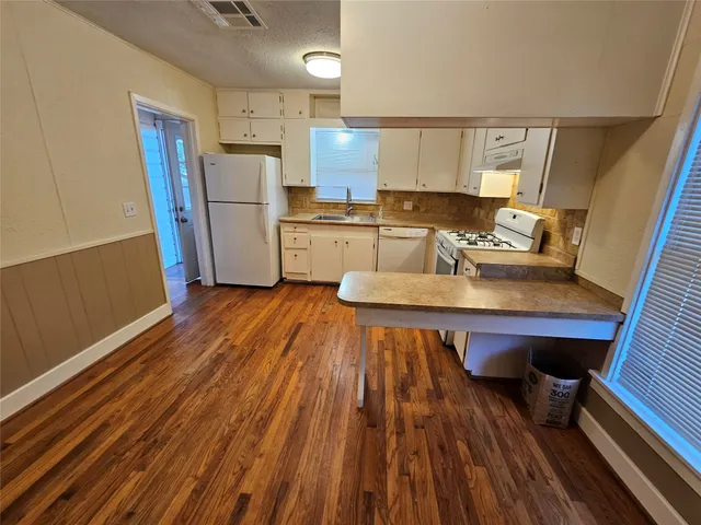 a kitchen with wooden floors and wooden cabinets