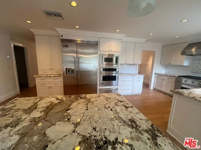 a kitchen with granite countertop a refrigerator and a stove top oven