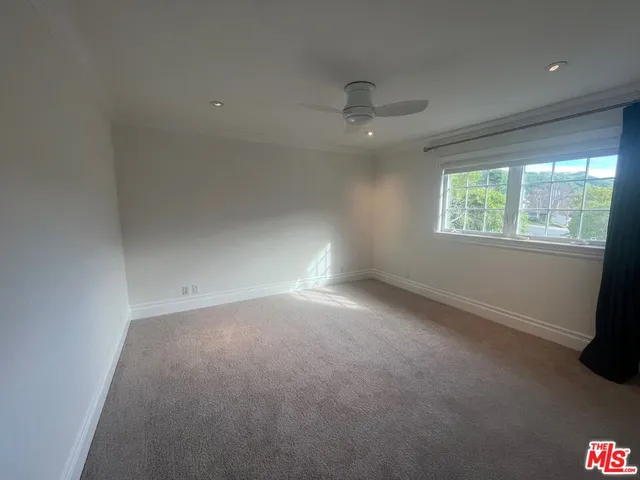 an empty room with windows and ceiling fan