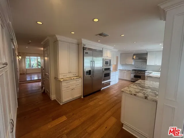 a kitchen with stainless steel appliances granite countertop a refrigerator and a stove top oven