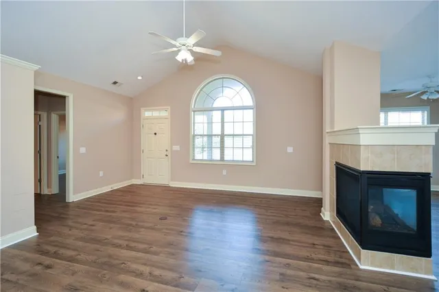 an empty room with wooden floor fireplace and windows