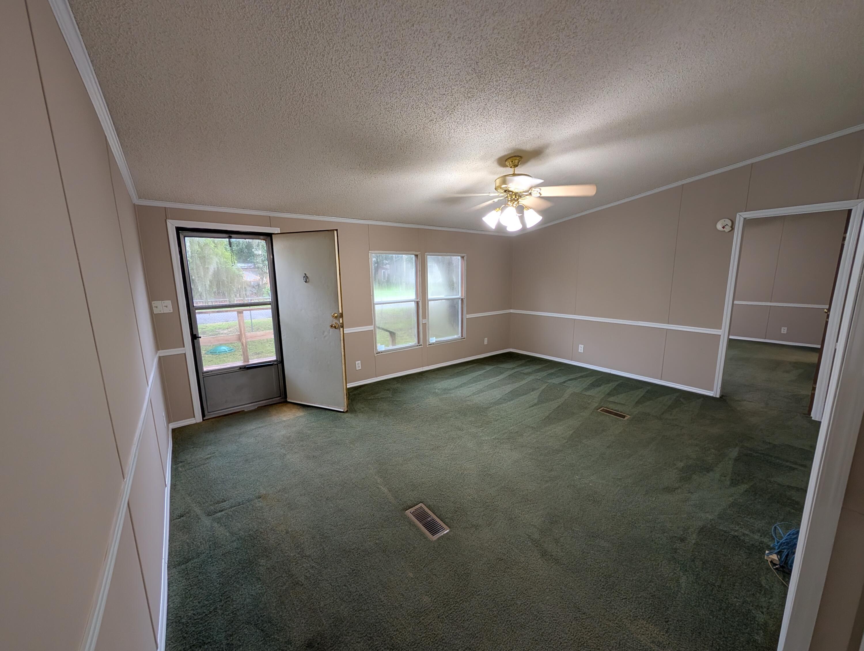 157 East Harborview Road Santa Rosa Beach, FL 32459 - Photo 7 of 27 an empty room with chandelier fan and windows