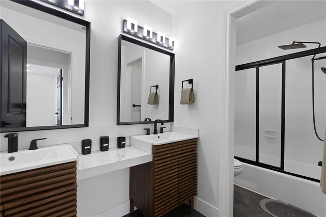 a bathroom with double vanity sink and two mirror