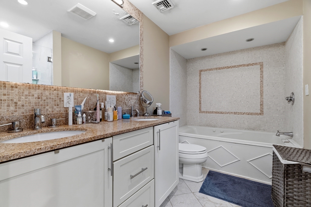 98 Waltham Street, Unit 1 Boston, MA 02118 - Photo 11 of 26 a bathroom with a granite countertop bathtub sink vanity mirror and toilet