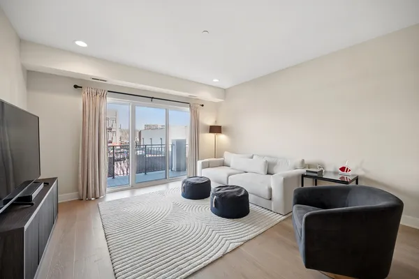 a living room with furniture a flat screen tv and a floor to ceiling window