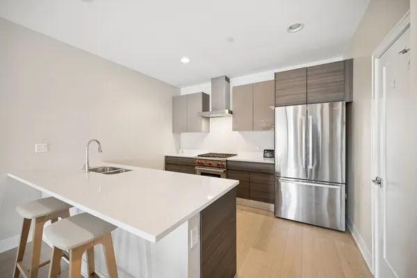 a kitchen with a refrigerator a sink and a stove top oven with wooden floor