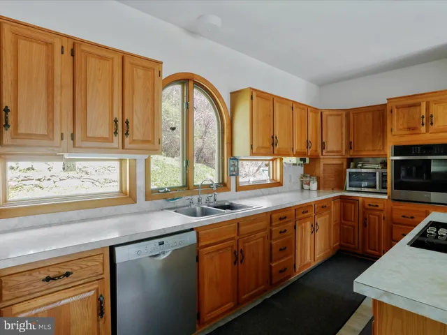 a kitchen with stainless steel appliances granite countertop a sink a stove and cabinets