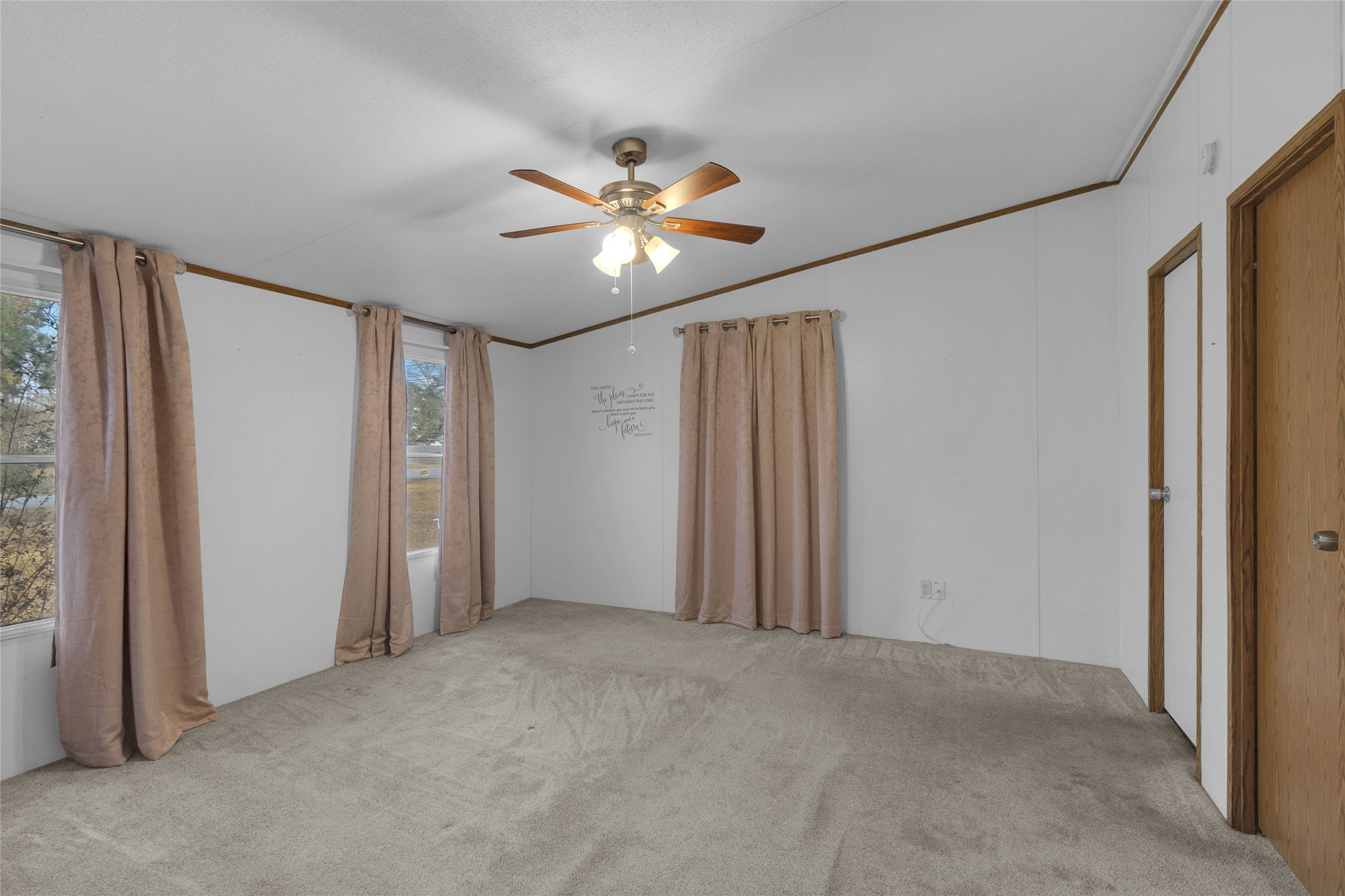 22094 Spear Road Porter, TX 77365 - Photo 20 of 45 This primary bedroom offers a generous carpeted space with white walls and a ceiling fan. Sunlight streams through the large window with patterned curtains, enhancing the airy and welcoming atmosphere.