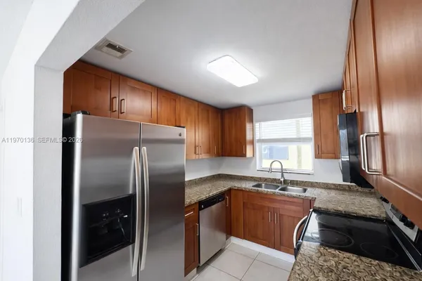 a kitchen with stainless steel appliances granite countertop a refrigerator sink and stove