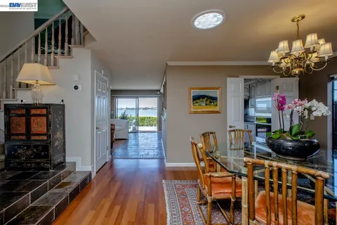 a living room with stainless steel appliances kitchen island granite countertop a refrigerator a stove a microwave oven a dining table and chairs with wooden floor