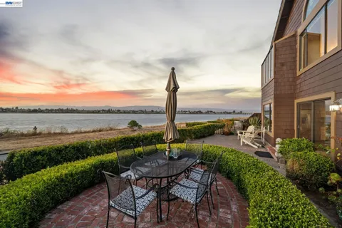a view of a patio with lawn chairs floor to ceiling window and an outdoor kitchen