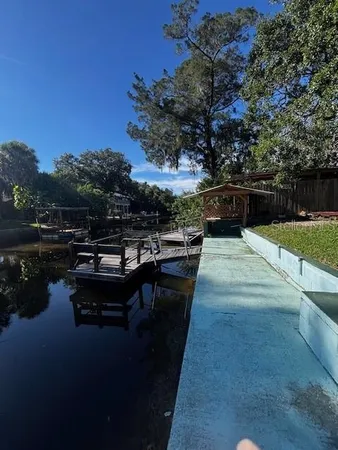 a swimming pool with outdoor seating and covered with trees