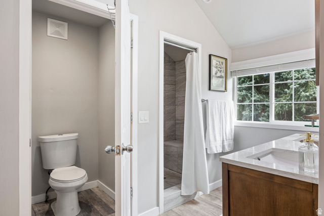 75 East 100 North Midway, UT 84049 - Photo 18 of 43 Bathroom featuring a wood-finish vanity with an integrated sink, a large window, a shower with a tiled surround, and wood-finish flooring