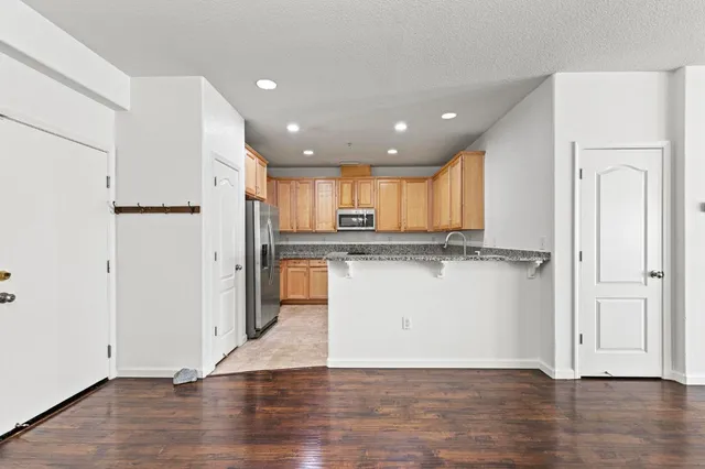 an open kitchen with wooden floor and stainless steel appliances