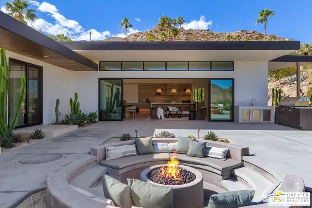 a living room with furniture a potted plant and a kitchen view