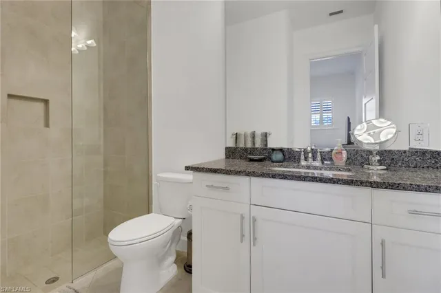 a bathroom with a granite countertop sink a toilet and a mirror