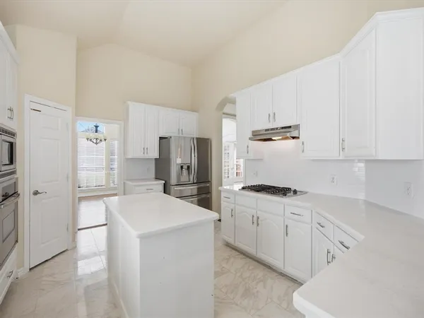 a kitchen with stainless steel appliances a refrigerator stove and white cabinets