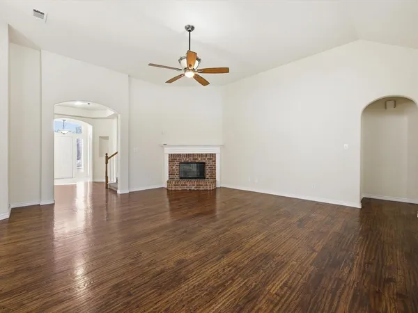 a view of empty room with wooden floor and ceiling fan