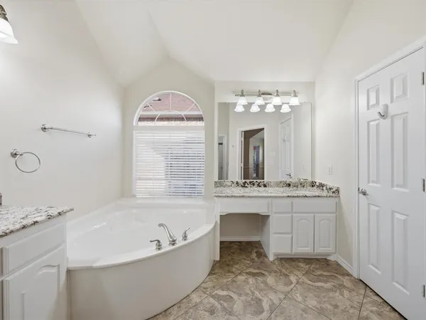 a spacious bathroom with a tub sink and mirror