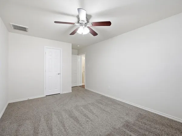 an empty room with a chandelier fan and windows
