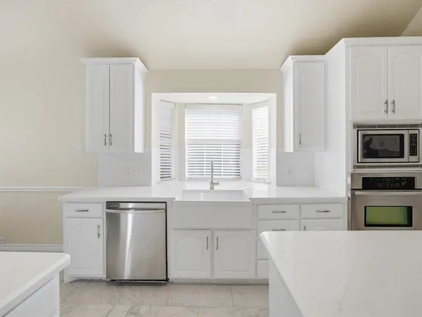 a kitchen with white cabinets and white appliances