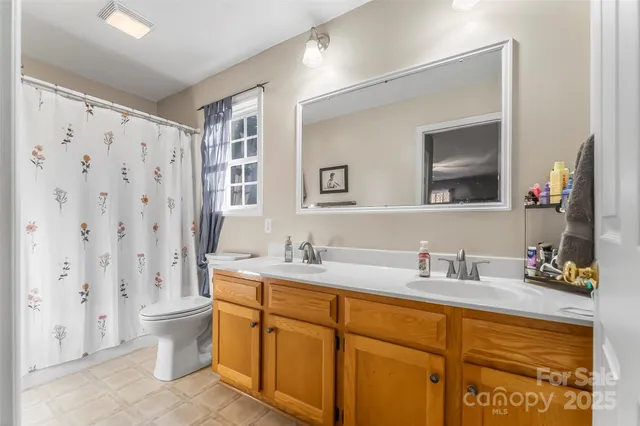 a bathroom with a double vanity sink toilet and a mirror