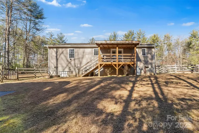 a view of a large house with a large tree and wooden fence