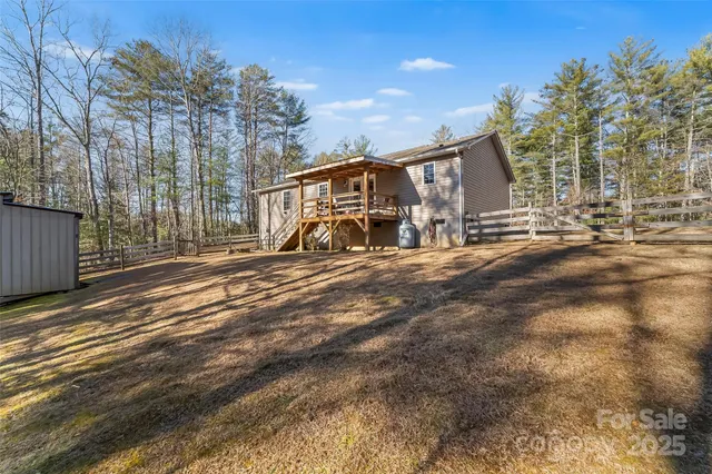 a view of backyard with large trees and wooden fence