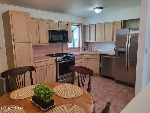 a kitchen with stainless steel appliances granite countertop a stove a sink dishwasher a refrigerator with a dining table and chairs
