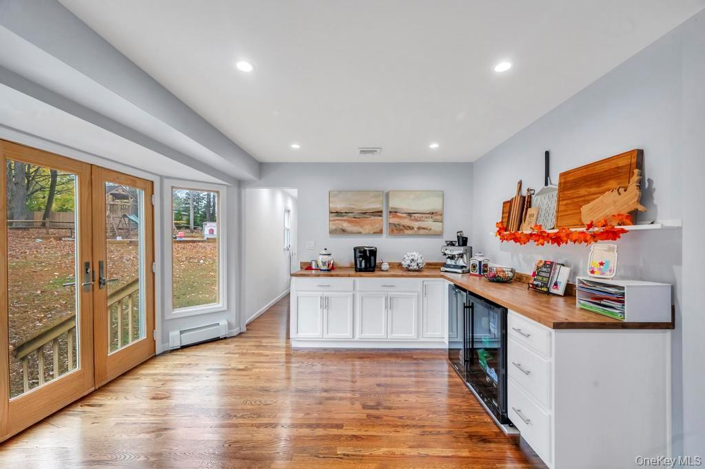 39 Bevin Road Northport, NY 11768 - Photo 14 of 44 Bar with white cabinetry, light wood-type flooring, recessed lighting, wooden counters, and beverage cooler
