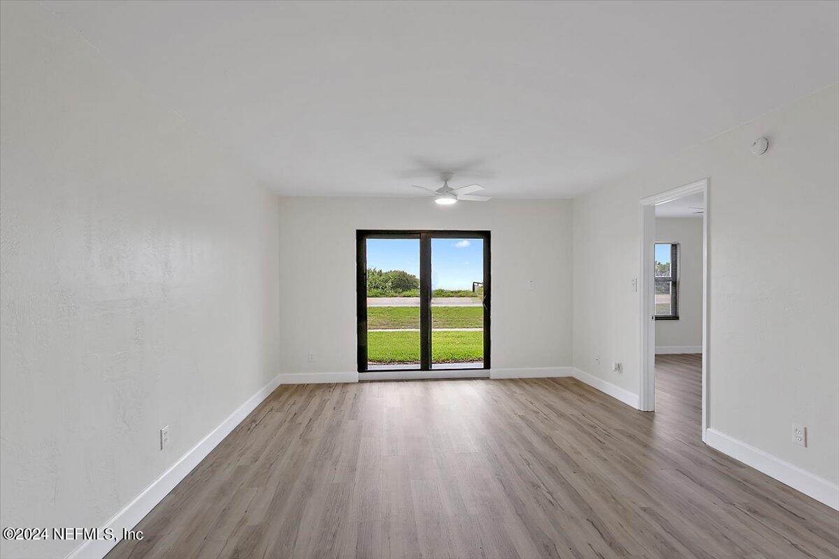 3100 Ocean Shore Boulevard, Unit 106 Ormond Beach, FL 32176 - Photo 4 of 21 an empty room with wooden floor and windows