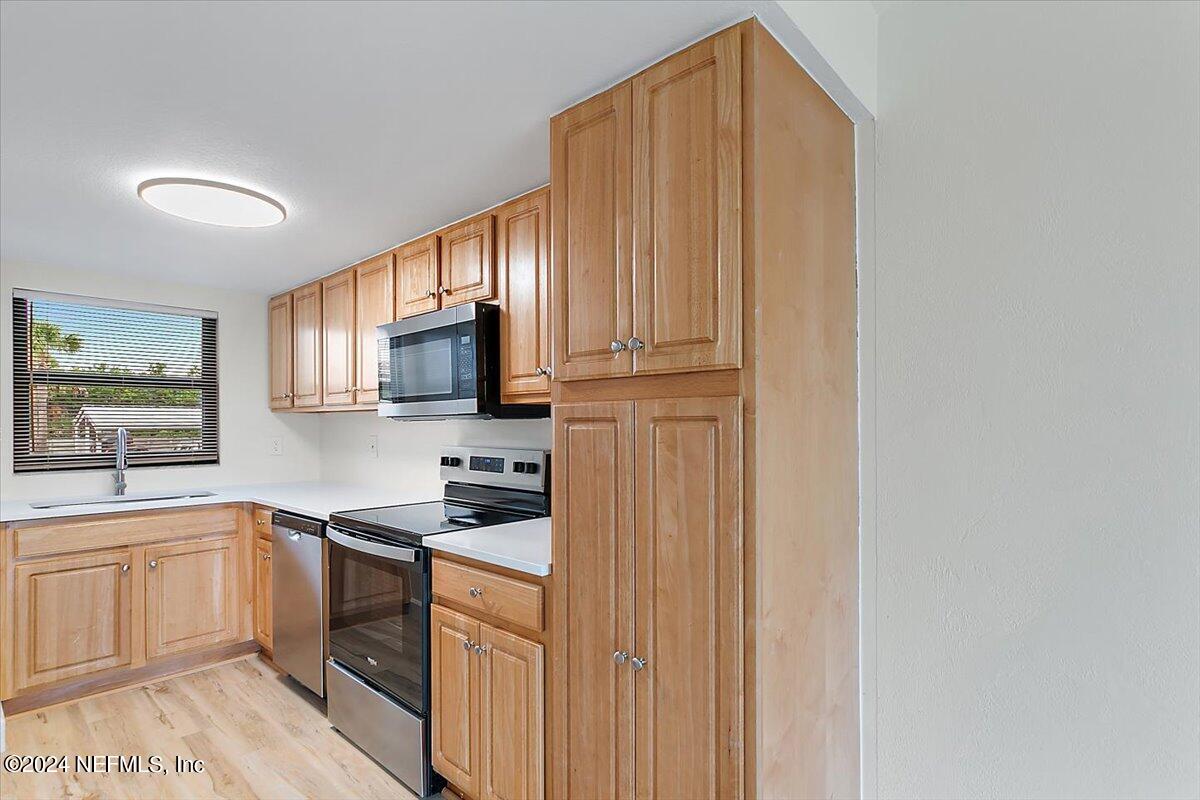 3100 Ocean Shore Boulevard, Unit 106 Ormond Beach, FL 32176 - Photo 5 of 21 a kitchen with stainless steel appliances granite countertop a refrigerator a sink dishwasher and wooden cabinets with wooden floor