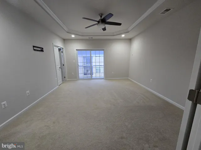 an empty room with chandelier fan and windows