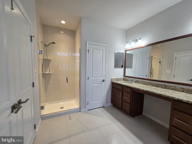 a spacious bathroom with a granite countertop sink mirror and shower