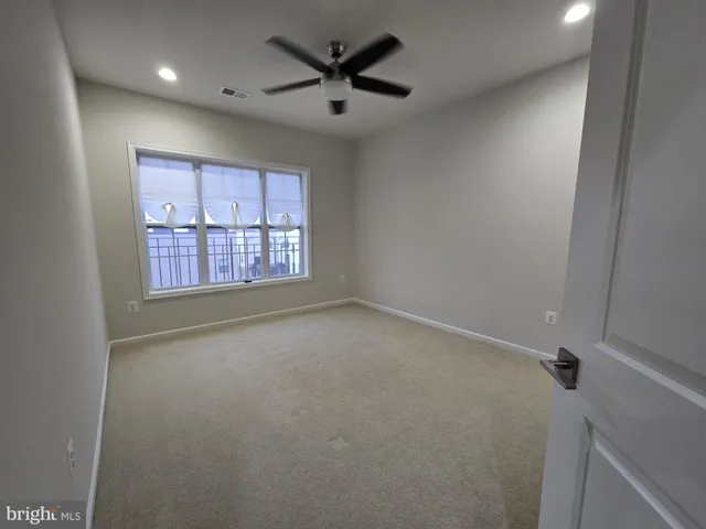 an empty room with windows and ceiling fan
