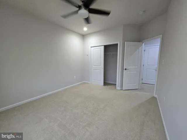 an empty room with a ceiling fan and bathroom