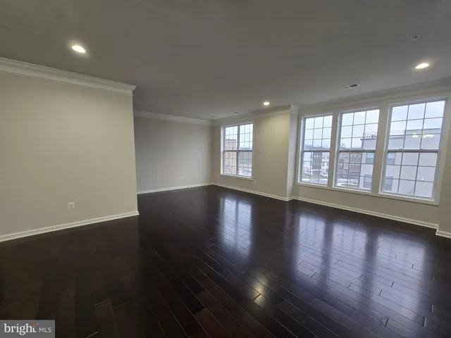 an empty room with wooden floor and windows with curtains