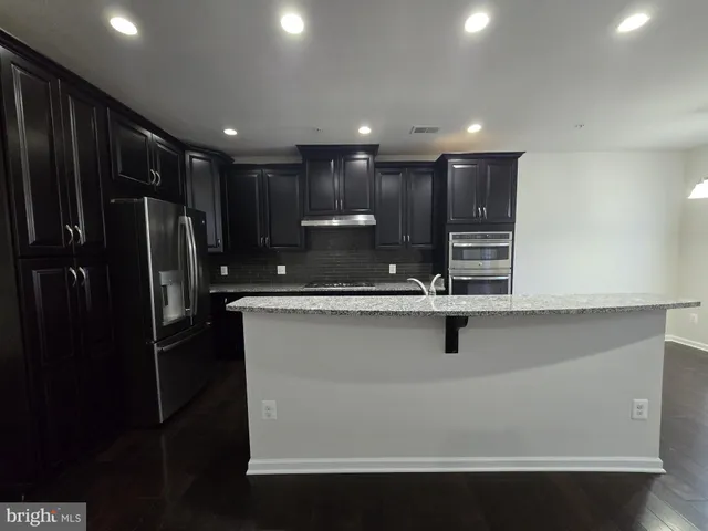 a view of kitchen with refrigerator stove and cabinets