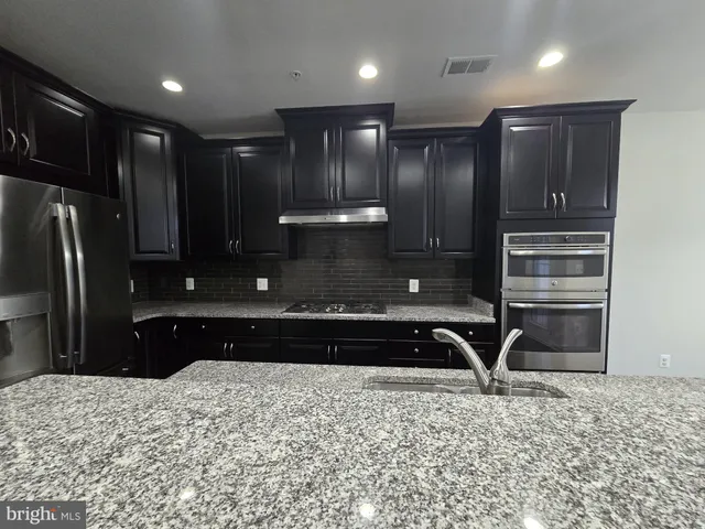 a bathroom with a granite countertop sink a refrigerator and a granite counter tops
