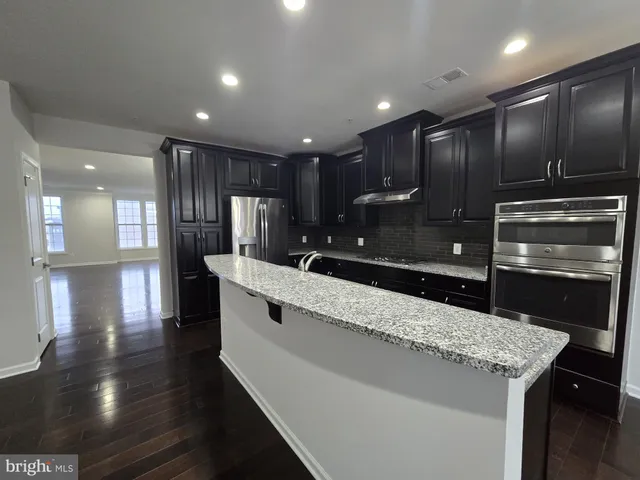 a large kitchen with granite countertop a large counter top stainless steel appliances and cabinets
