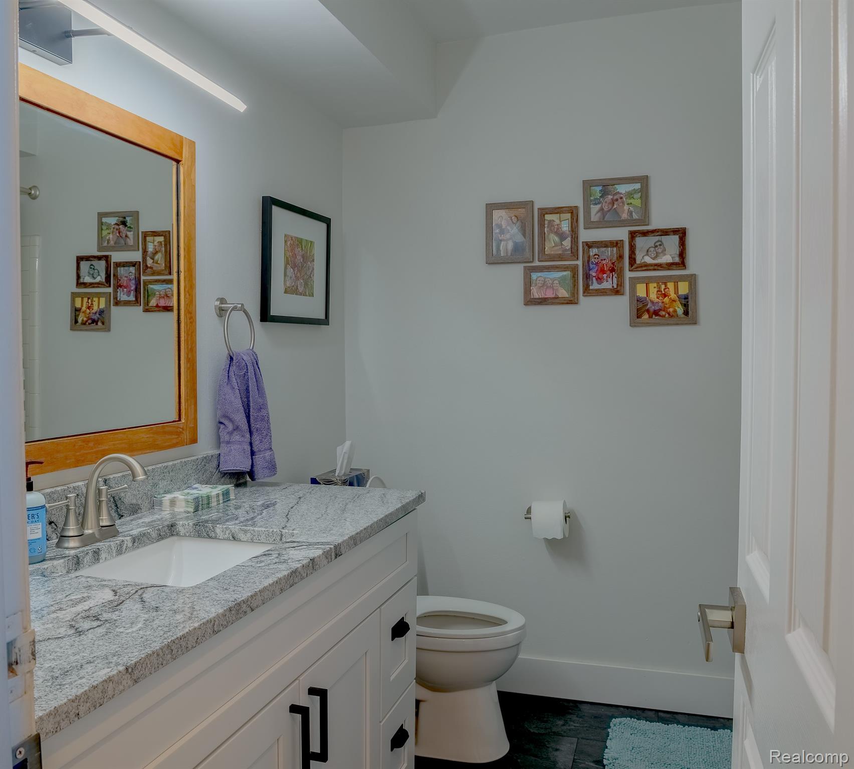 1989 Klingensmith Road, Unit 46 Bloomfield Hills, MI 48302 - Photo 16 of 41 Bathroom featuring a white vanity with a light-toned patterned countertop, an undermount sink, and a framed mirror