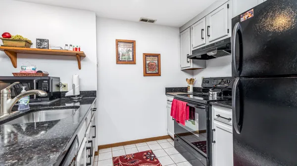 a kitchen with stainless steel appliances granite countertop a sink refrigerator and cabinets