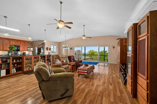 a living room with furniture a ceiling fan and a floor to ceiling window