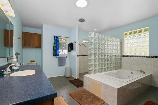 a bathroom with a sink double vanity granite tub shower and a mirror