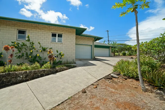 a front view of a house with a yard and potted plants