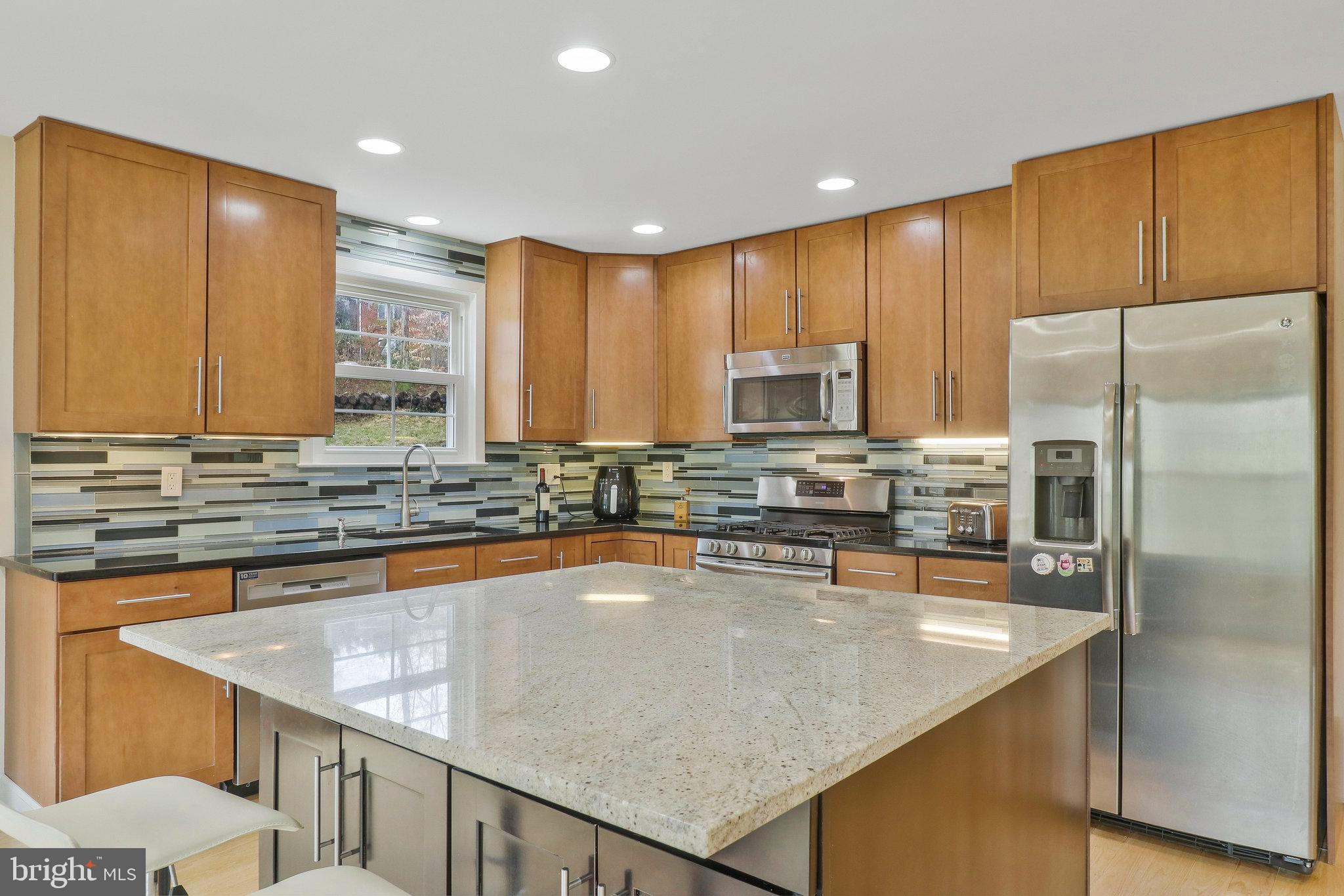 8543 Howell Road Bethesda, MD 20817 - Photo 9 of 24 a kitchen with stainless steel appliances granite countertop a refrigerator a stove and a sink with wooden floor